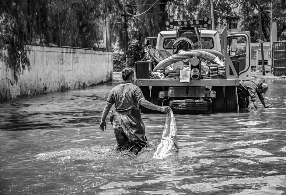 A black and white photo depicting flood cleanup efforts in an urban setting, showcasing resilience.